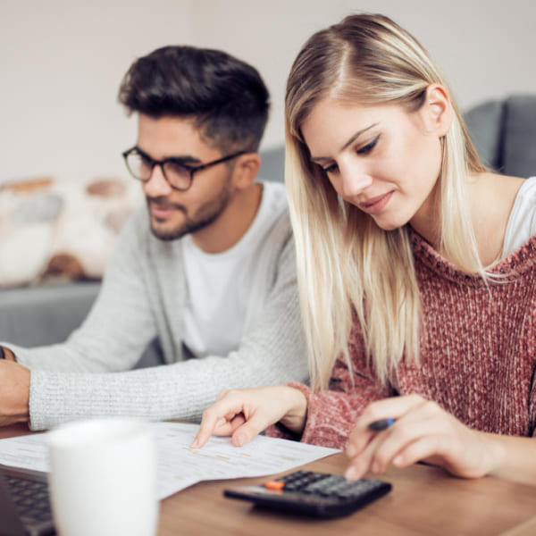 Couple evaluating loan options with documents and calculator, deciding on easy approval loans.