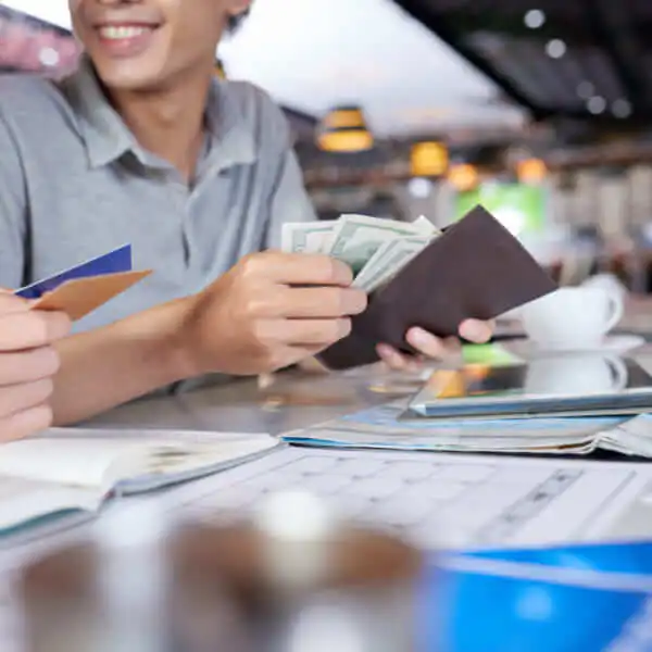 A smiling person holding a wallet full of cash and credit cards, representing fast loan approval.