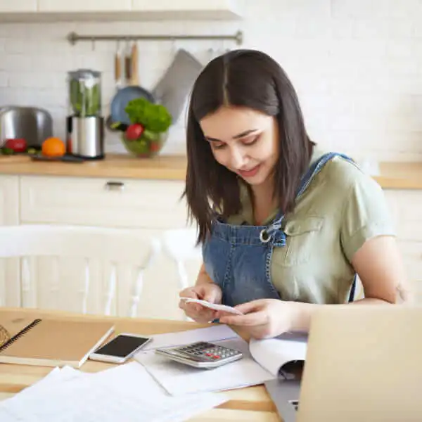 A close-up of a person's hands holding a smartphone and a credit card over a desk with documents, evaluating when to use this type of financing.