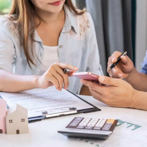 A happy couple in their living room looking at a laptop and holding a credit card, discussing why online personal loans are becoming popular.